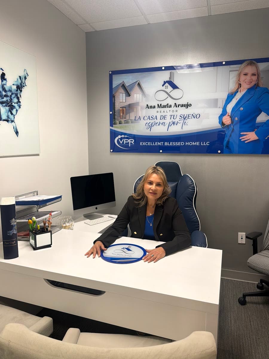 Ana María Araujo en su escritorio, con su banner de Excellent Blessed Home LLC